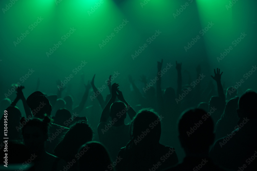 silhouettes of hands on concert in front of bright stage lights