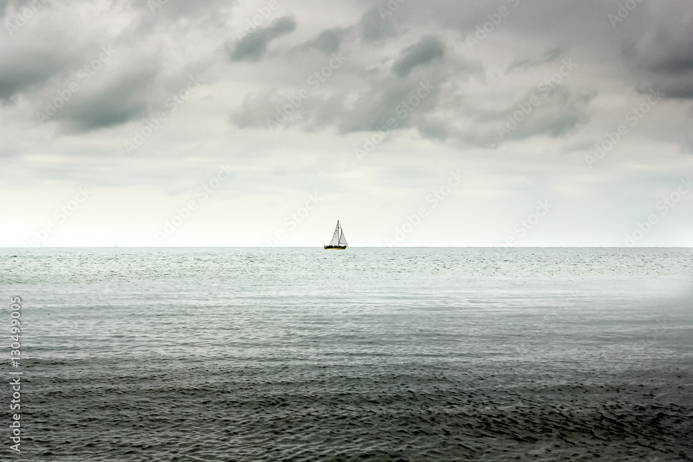 Single lone boat in Deep sea and heavy overcast clouds Single lone boat in Deep sea and heavy overcast clouds