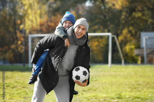Father and son with ball on soccer pitch