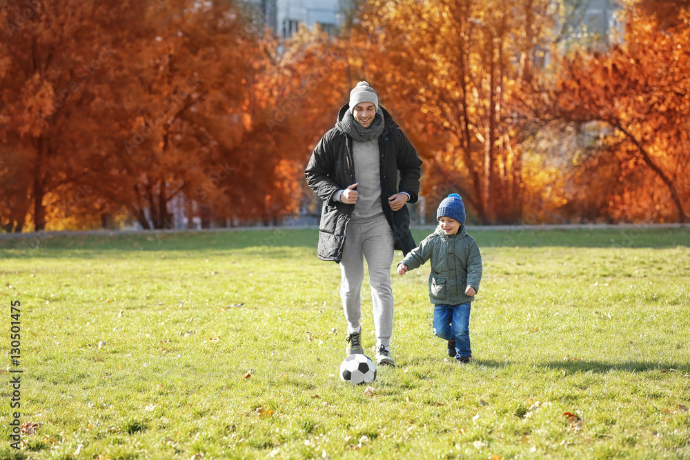 Father and son playing football on soccer pitch Father and son playing football on soccer pitch
