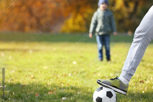 Father and son with ball on soccer pitch, close up view