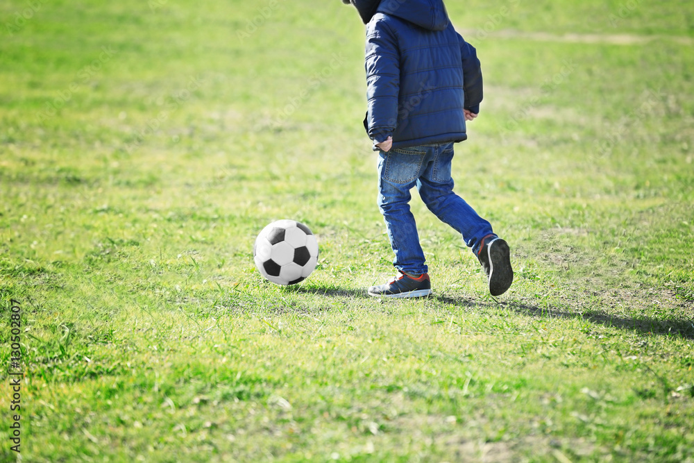 Cute little boy playing football on soccer pitch Cute little boy playing football on soccer pitch