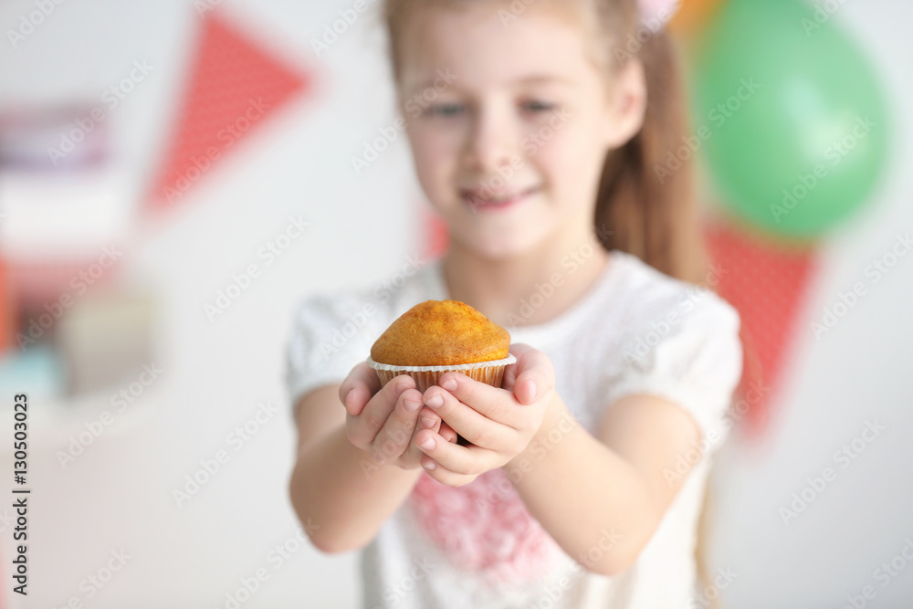 Little girl holding tasty muffin on blurred background, close up Little girl holding tasty muffin on blurred background, close up
