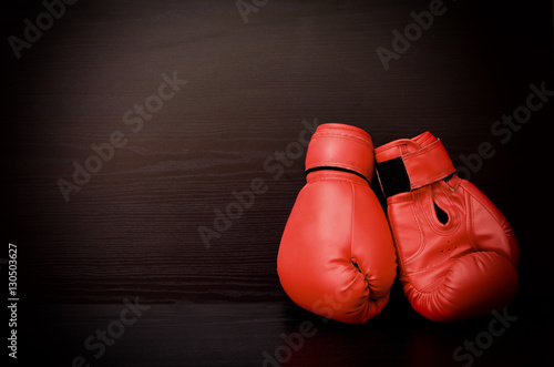 Two red boxing gloves on the side of the frame on a black background, empty space © somemeans