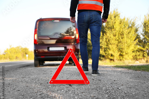 Tow truck worker near red warning triangle on asphalt road © Africa Studio