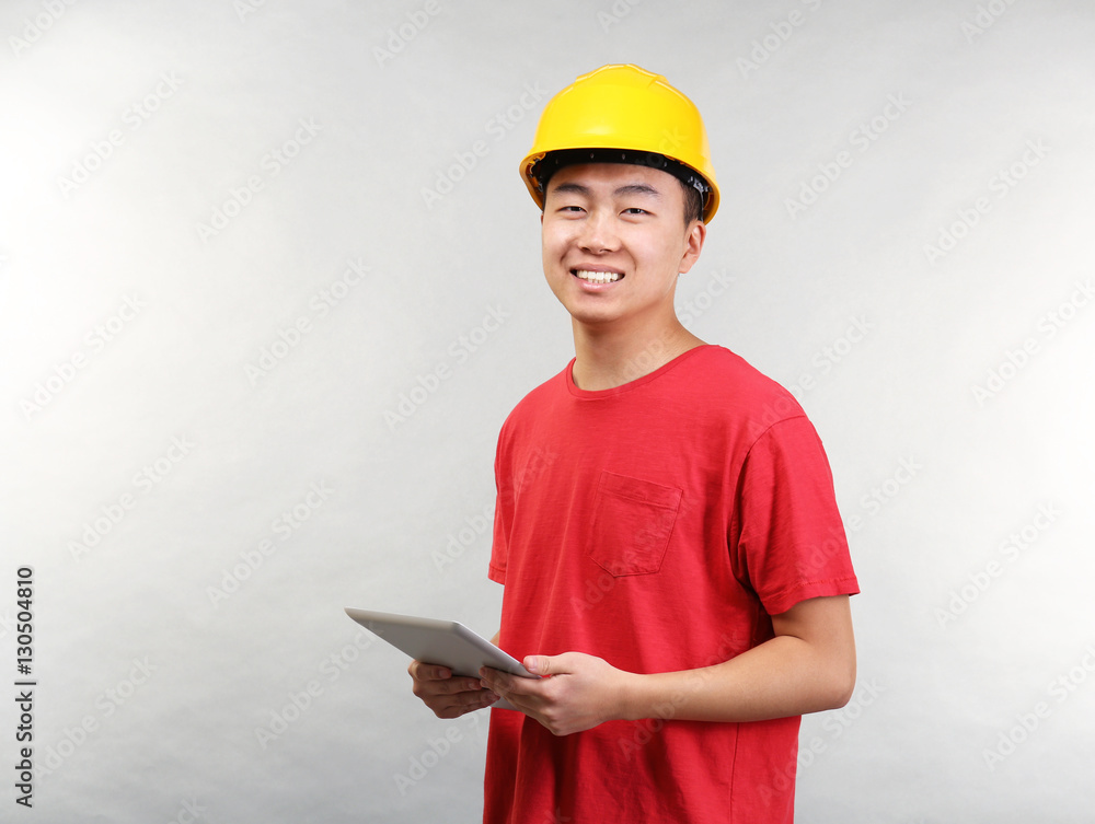 Asian warehouse worker with tablet computer on light background Asian warehouse worker with tablet computer on light background