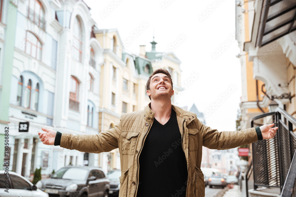 Joyful young man walking on the street and looking up Joyful young man walking on the street and looking up