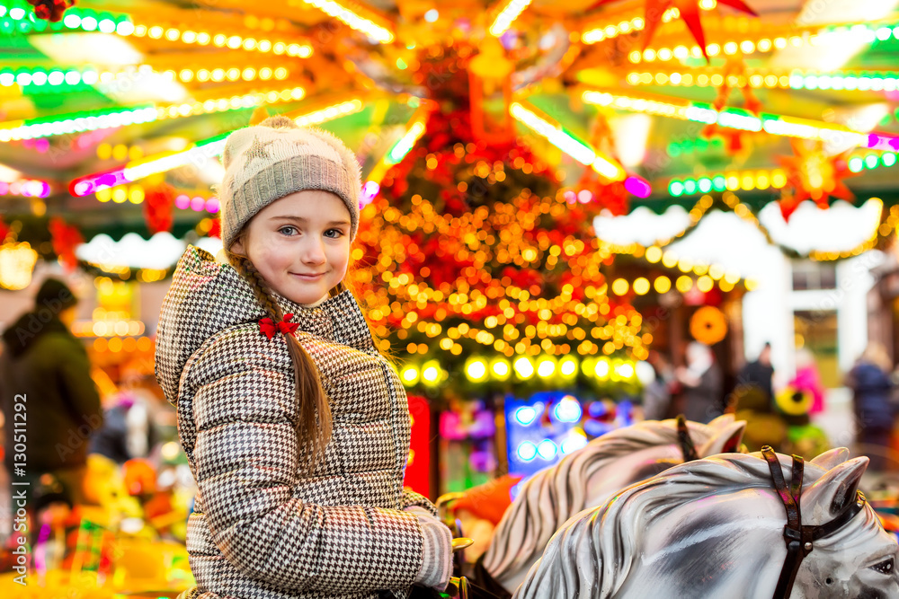 Portrait of a happy little girl riding on horses on carousel, tr
