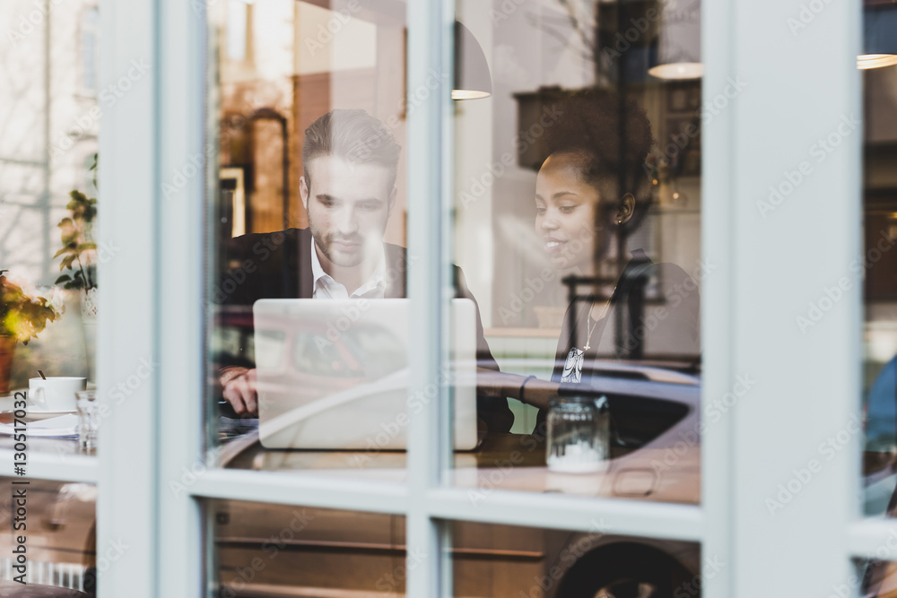 Young businessman and woman using laptop in a cafe Young businessman and woman using laptop in a cafe