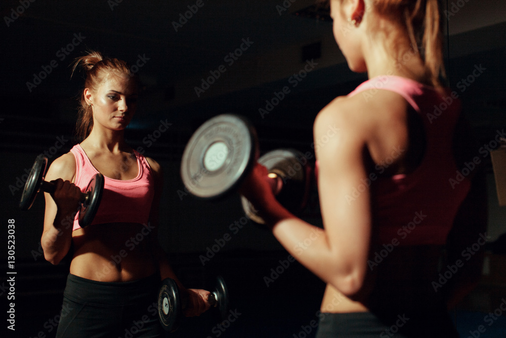 Plakat Young girl doing exercise for biceps with dumbbells