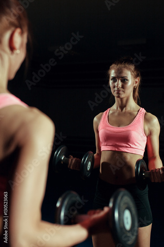 Young woman with a dumbbell in the gym.