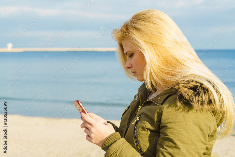 Woman using her smartphone outside, sunny day