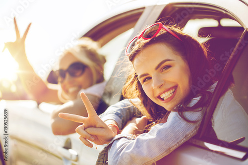 happy teenage girls or women in car at seaside