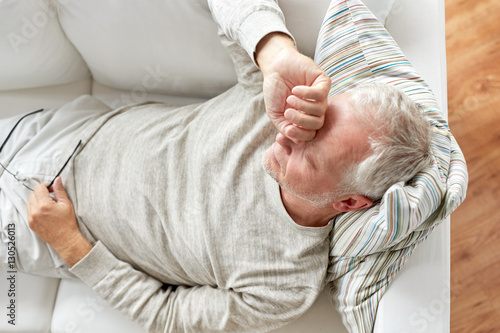 close up of tired senior man lying on sofa at home photo