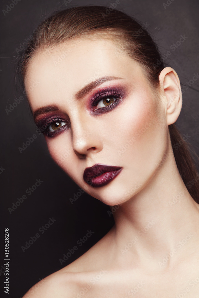 Fototapeta premium Portrait of young beautiful woman with stylish dark eyeshadow and lipstick