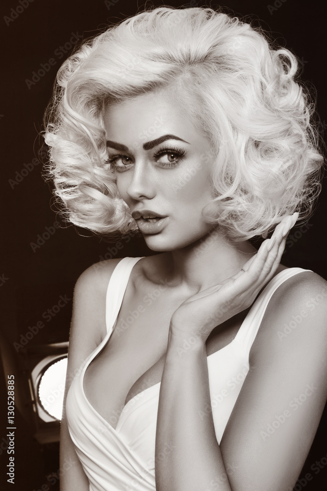 Vintage style black and white portrait of young beautiful glamorous woman with platinum blonde curly hair