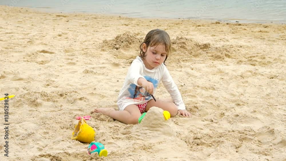 Little cheerful child playing in the sand on the seashore. The concept of summer family vacation. Little cheerful child playing in the sand on the seashore. The concept of summer family vacation.