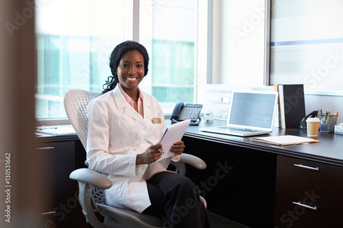 Portrait Of Female Doctor Wearing White Coat In Office