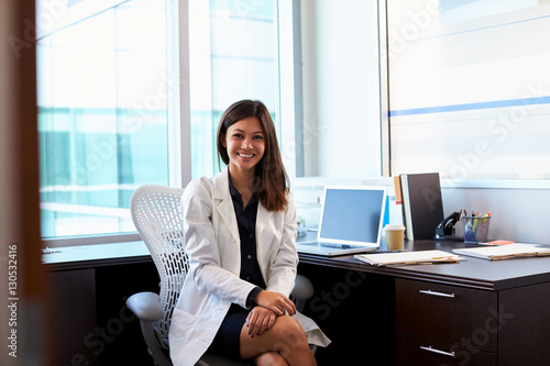Portrait Of Female Doctor Wearing White Coat In Office