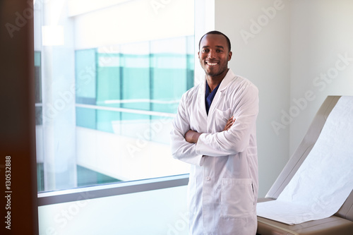 Schilderij op canvas Portrait Of Male Doctor Wearing White Coat In Exam Room