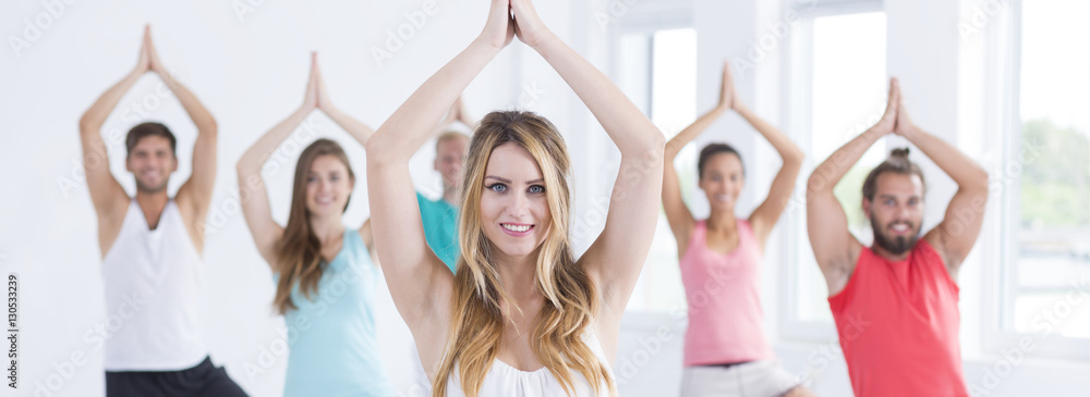 Fototapeta premium Yoga teacher with people doing vrikshasana