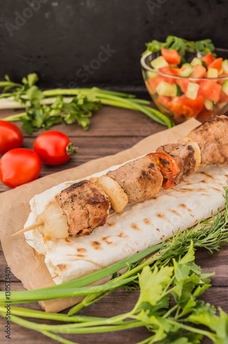 Pork cooked with vegetables on skewers  a wooden background