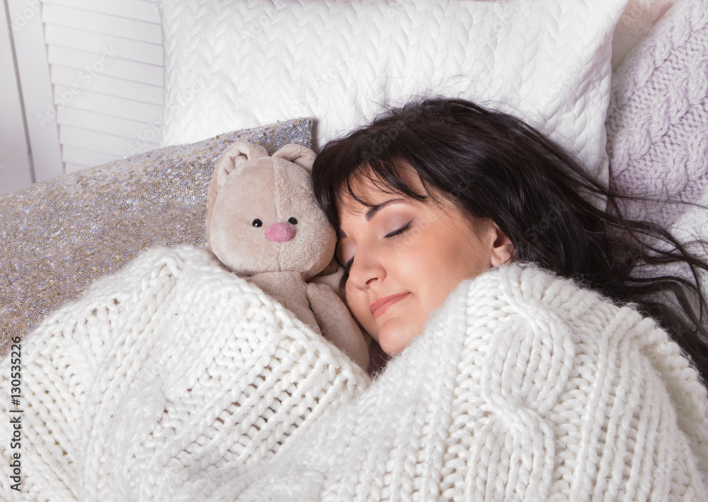 Girl sleeps in a bed with a toy a teddy bear