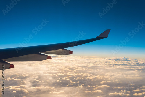 Wing of the air plane on the sea of cloud sunset sky background