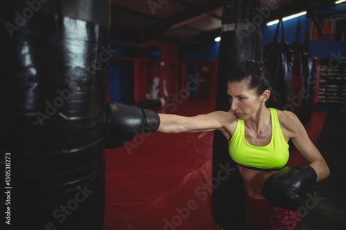 Female boxer practicing boxing with punching bag