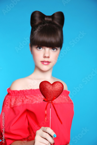 Red heart in teen girl hand. Brunette young model  with bow hair
