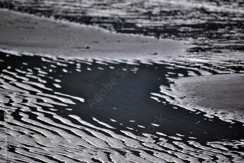 acqua e sabbia che formano strani disegni e colori in inverno sulla spiaggia a riva photo