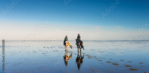 deux cavalières se promenant sur la plage