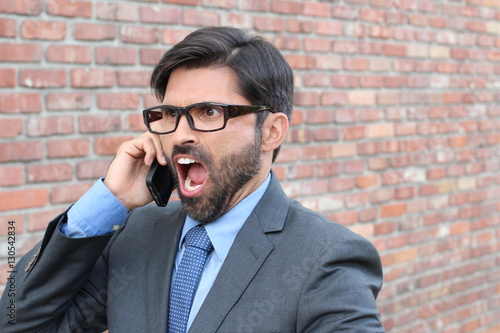 Absolutely furious businessman shouts into cell phone - Stock image