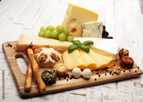 Cheese platter with different cheese and grapes - some emmental, gauda, parmesan and brie cheese on a table for brunch photo