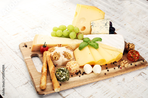 Cheese platter with different cheese and grapes - some emmental, gauda, parmesan and brie cheese on a table for brunch photo