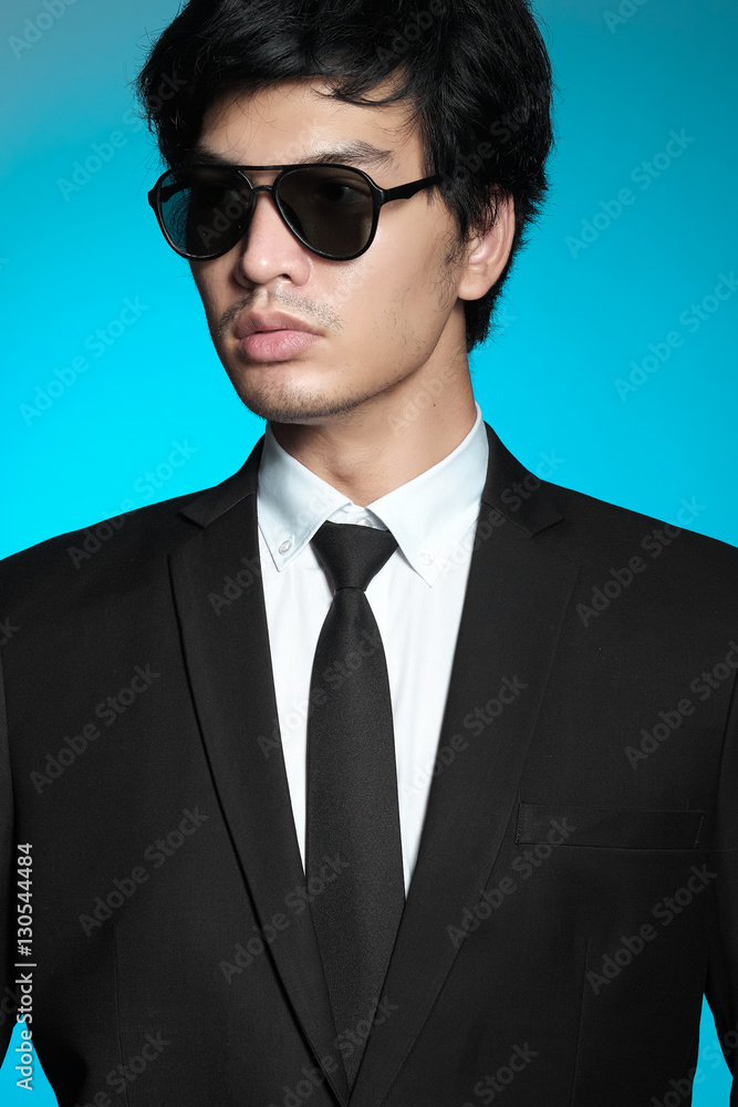 Asian man in black suit and white shirt on blue background Asian man in black suit and white shirt on blue background