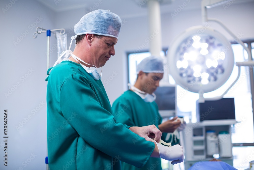 Obraz premium Surgeon wearing surgical gloves in operation theater