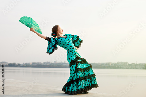 Woman in long green dress stay in dancing pose