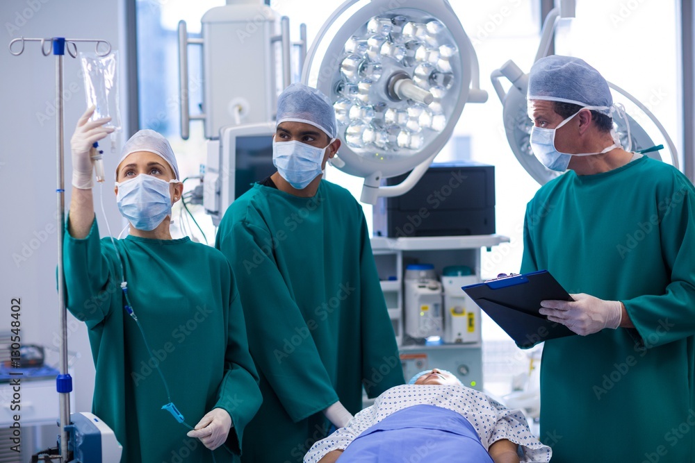 Surgeons adjusting iv drip in operation theater Surgeons adjusting iv drip in operation theater
