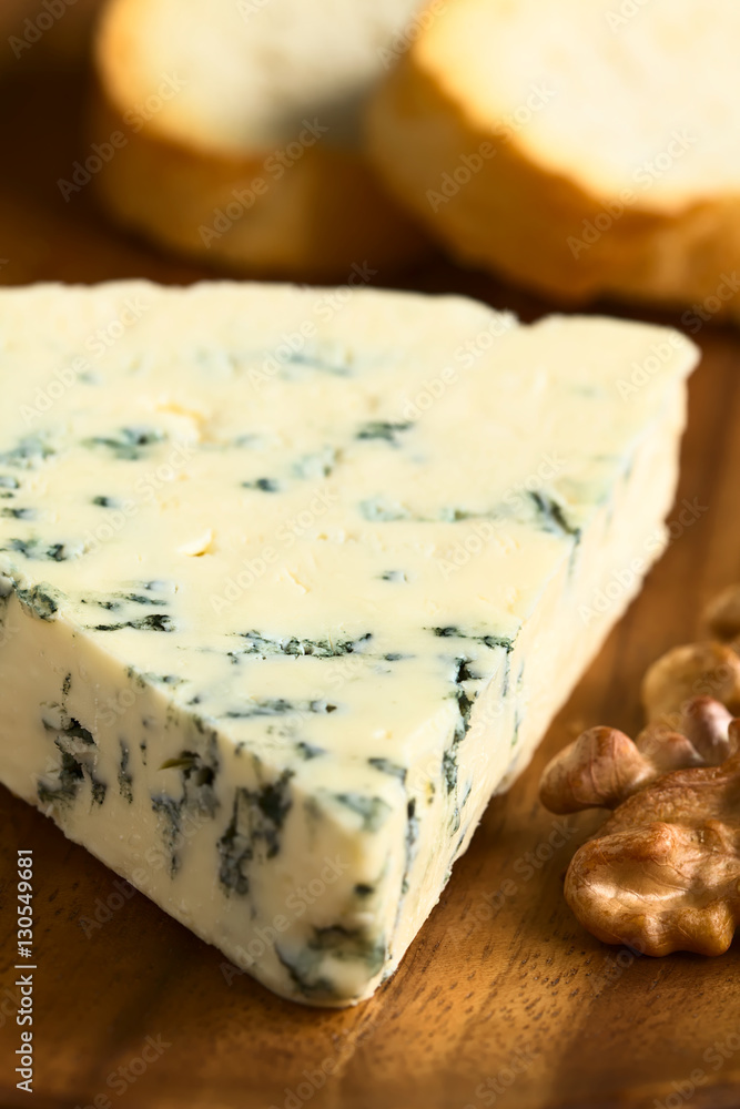 Blauschimmelkäse mit Walnuss und Brotscheiben auf Holzbrett, fotografiert mit natürlichem Licht (Selektiver Fokus, Fokus ein Drittel in den Käse)