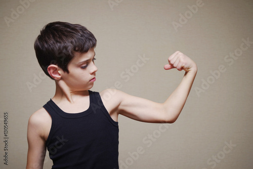 Fototapeta Boy is showing his arm muscles