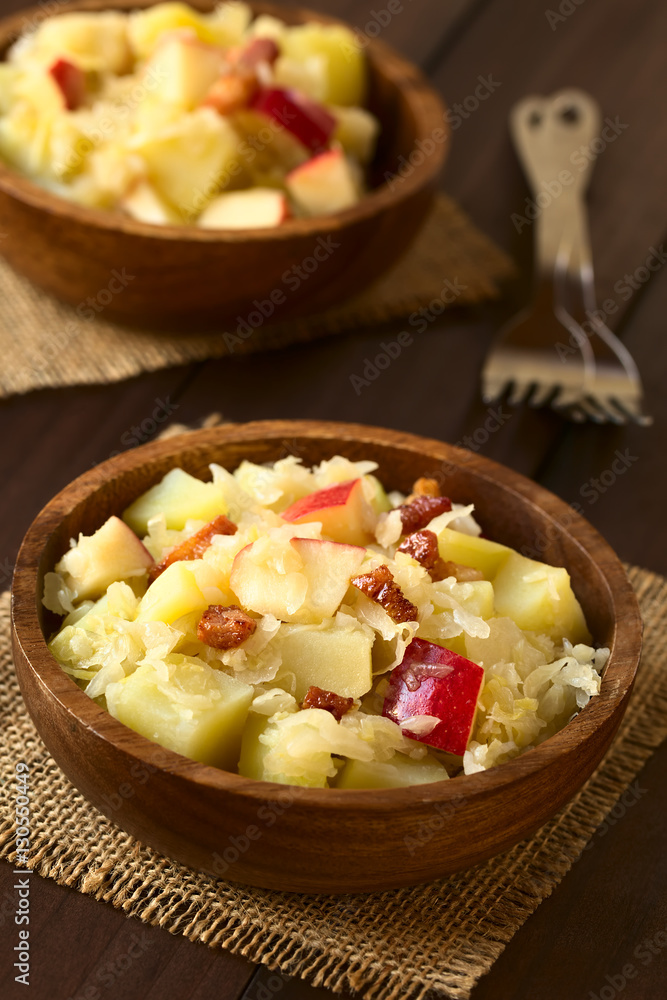 Salat aus Sauerkraut, Apfel, Kartoffeln und Speck in Holzschüssel, fotografiert mit natürlichem Licht (Selektiver Fokus, Fokus in die Mitte des ersten Salats) Salat aus Sauerkraut, Apfel, Kartoffeln und Speck in Holzschüssel, fotografiert mit natürlichem Licht (Selektiver Fokus, Fokus in die Mitte des ersten Salats)