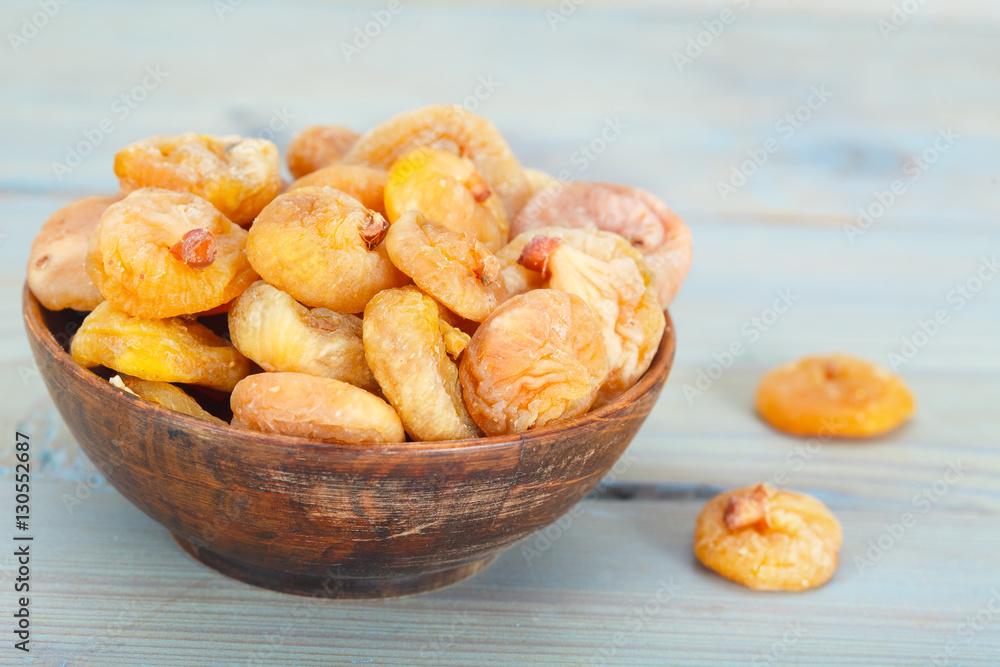 Fototapeta premium Delicious dried figs in wooden bowl over blue background