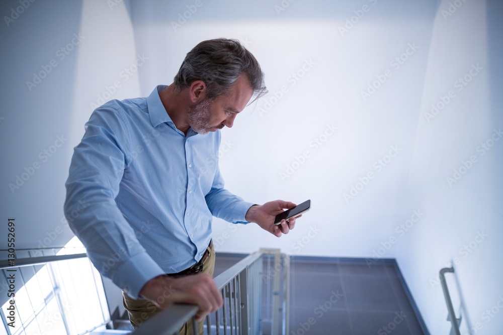 Doctor standing at staircase and using mobile phone