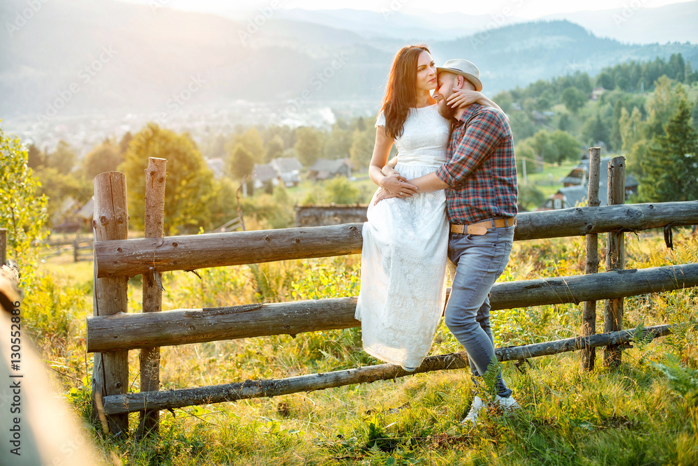 loving couple in the mountains near a wooden fence.
