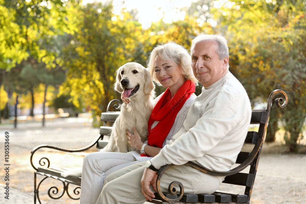 Senior couple and big dog sitting on bench in park Senior couple and big dog sitting on bench in park