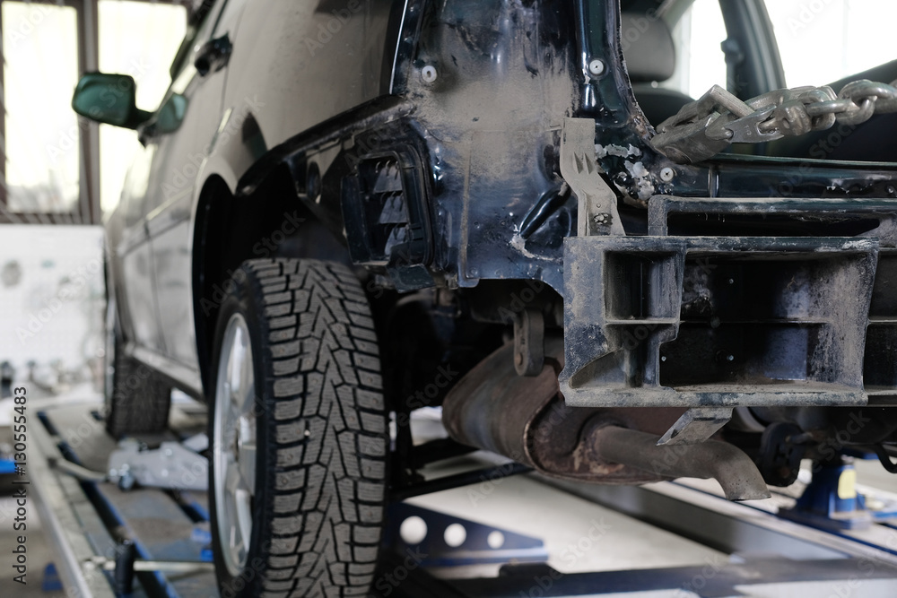 Fototapeta premium Black crashed car on stocks in a car repair station
