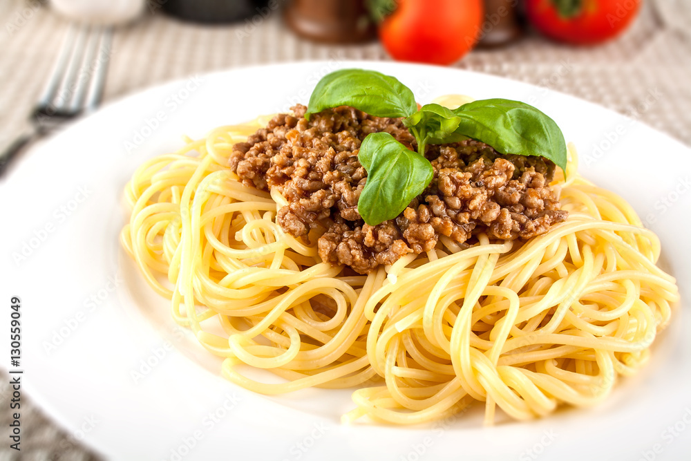Spaghetti bolognese with basil on white plate