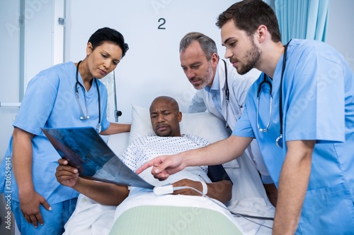 Doctor and nurse discussing x-ray with patient in ward