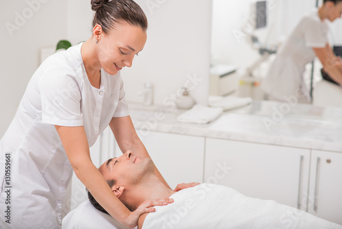Φωτογραφία Joyful masseuse massaging male shoulders